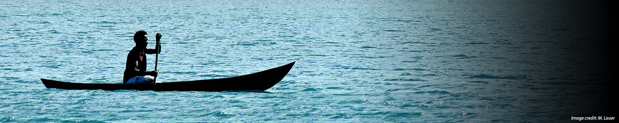 man paddles canoe in ocean