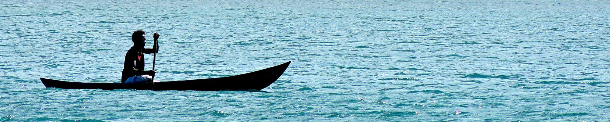 man paddles canoe in ocean